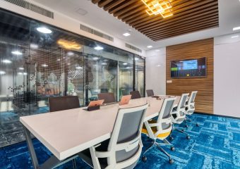 Sleek, contemporary office boardroom with glass walls, modern furniture, and digital screen display.